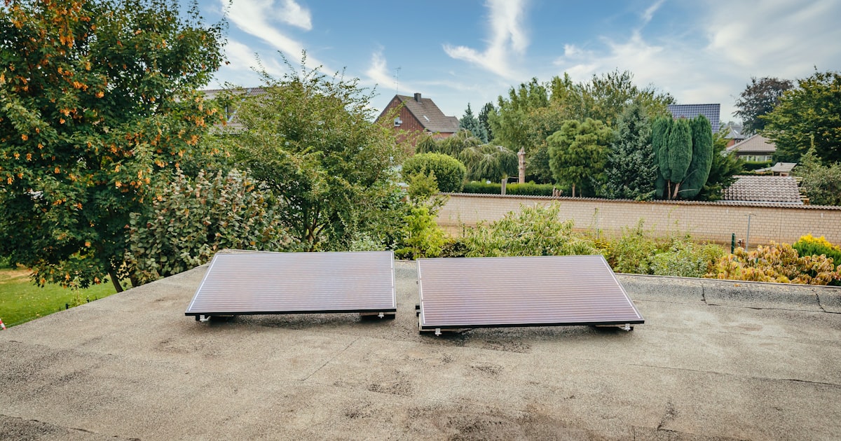 Two solar panels on a rooftop with trees.