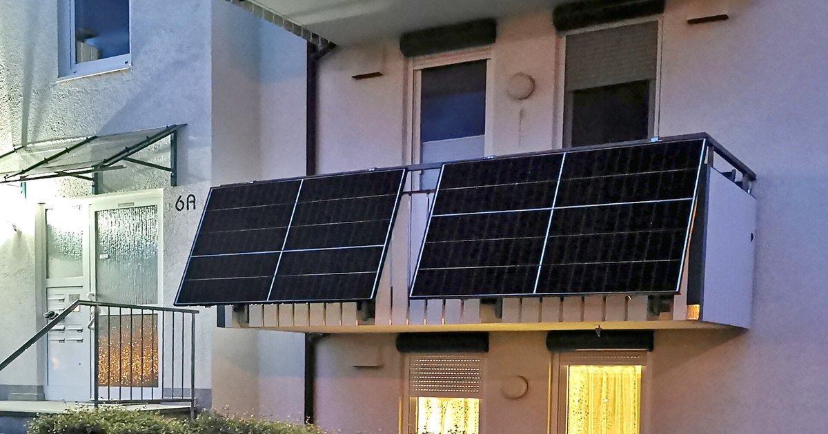 Zwei Solarmodule eines Balkonkraftwerks am Geländer eines Wohnhauses, bei Dämmerung