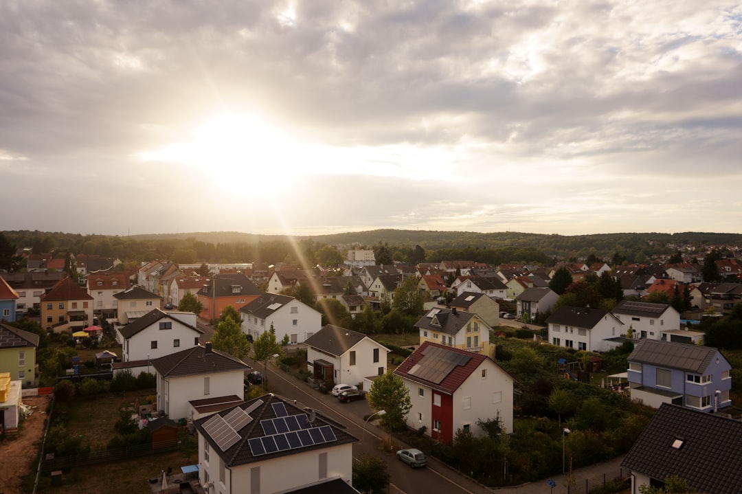 white and brown houses near green trees under white clouds during daytime